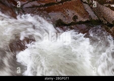 Superbes détails en gros plan et formes de rapides puissants de Mountain creek en cascade sur des rochers rouges et humides d'un canyon Banque D'Images