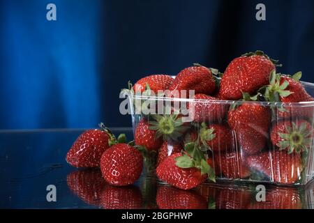 fraises se rapprochanent sur un fond bleu foncé. Mode de vie sain. Cocktail multivitamine. Régime d'été. Ensemble de fruits. Chute de fraises Banque D'Images