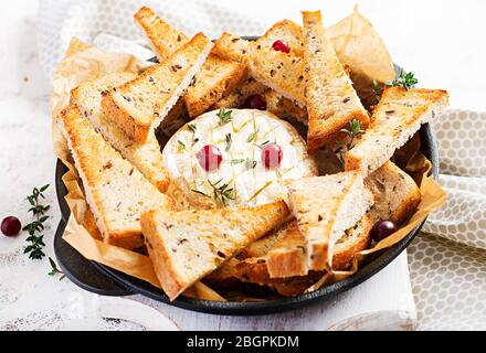 Camembert cuit au four avec toasts et thym sur fond clair. Banque D'Images