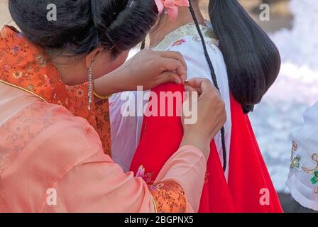 Une femme qui ajuste un costume traditionnel chinois lors d'un événement culturel à Calgary, Alberta Canada Banque D'Images