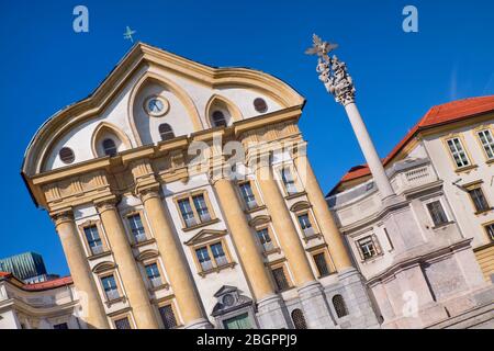 Slovénie, Ljubljana, Église Ursuline de la Sainte Trinité à Kongressni Trg ou place du Congrès avec la colonne Sainte Trinité à droite. Banque D'Images