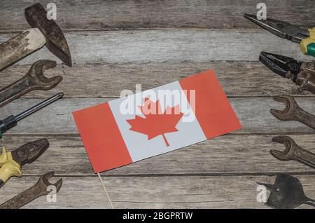 La fête du travail au Canada. Drapeau du Canada sur les planches en bois avec outils rouillés avec espace de copie. Banque D'Images