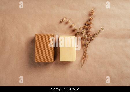 Savon avec boîte de carton à volants et herbes sèches sur papier naturel rustique. Concept de santé et de beauté. Banque D'Images