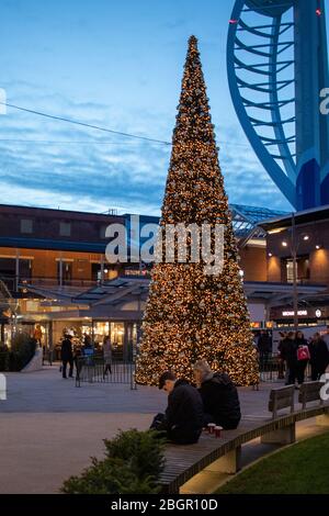 L'arbre de Noël entouré de clients de Gunwharf Quays, Portsmouth avec la tour Spinnaker dans le backgroun Banque D'Images