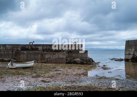 Bateau à ramer attaché à un bolard de mouton et amarré sur le bord de mer à quai près de Corrie sur l'île d'Arran, en Écosse Banque D'Images