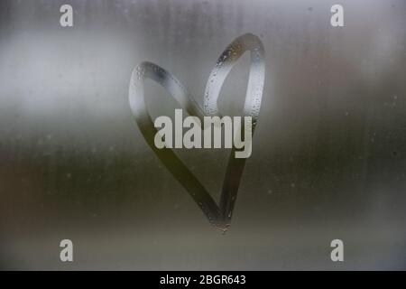 Beau symbole d'amour de coeur sur la fenêtre de verre avec des gouttes d'eau. Banque D'Images