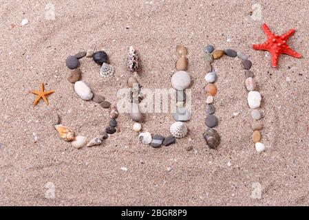 Mot soleil fait de coquillages et de pierres sur le sable Banque D'Images