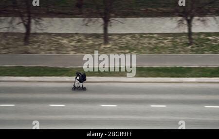 Vue latérale d'un homme portant un casque sur un scooter électrique qui monte dans la rue Banque D'Images