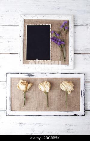 Cadres en bois avec fleurs séchées et photo vierge sur fond en bois Banque D'Images