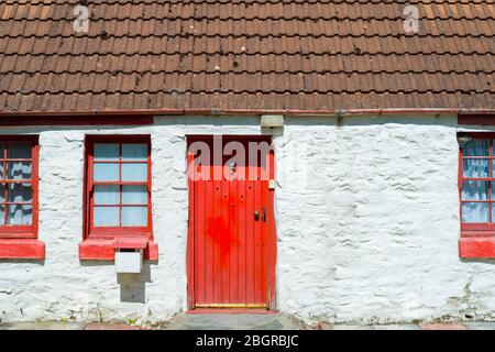 Pittoresque cottage traditionnel blanchi à la chaux avec porte rouge vif et fenêtres à Argyll et Bute, en Écosse Banque D'Images