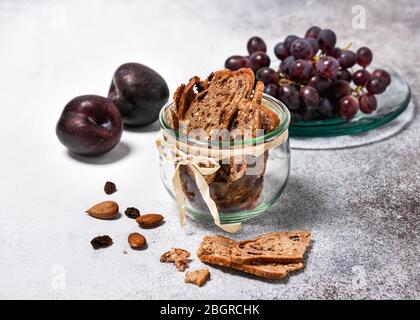 Tranches de pain de fruits à base de biseau sec dans un bocal en verre avec prunes et raisins frais. Concept de nourriture saine maison. Mise au point sélective. Banque D'Images