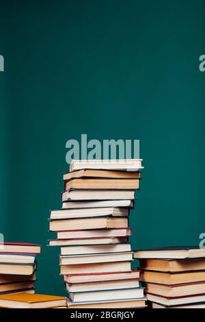 de nombreuses piles de livres éducatifs dans la bibliothèque universitaire sur un fond vert Banque D'Images