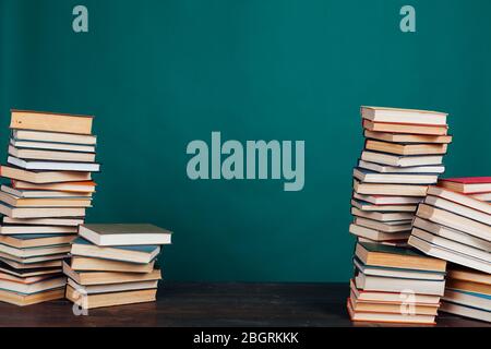 de nombreuses piles de livres éducatifs dans la bibliothèque universitaire sur un fond vert Banque D'Images