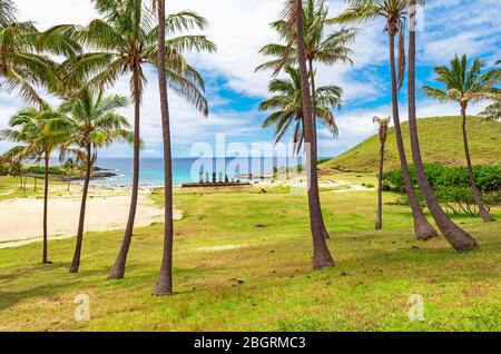 Palmiers sur la plage d'Anakena avec la silhouette du Moai du site archéologique AHU Nao Nao, Rapa Nui (île de Pâques), Chili. Banque D'Images