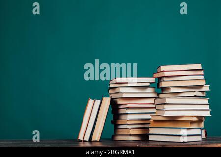 de nombreuses piles de livres éducatifs dans la bibliothèque universitaire sur un fond vert Banque D'Images