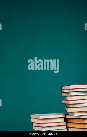 de nombreuses piles de livres éducatifs dans la bibliothèque universitaire sur un fond vert Banque D'Images