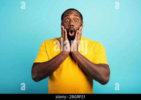 Surpris et choqué expression d'un garçon sur fond cyan Banque D'Images