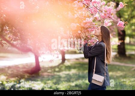 belle fille aime le parfum de l'arbre fleuri. Portrait de belle femme avec cerisier fleuri - fille inhale parfum des fleurs avec Banque D'Images