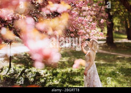 belle fille aime le parfum de l'arbre fleuri. Portrait de belle femme avec cerisier fleuri - fille inhale parfum des fleurs avec Banque D'Images