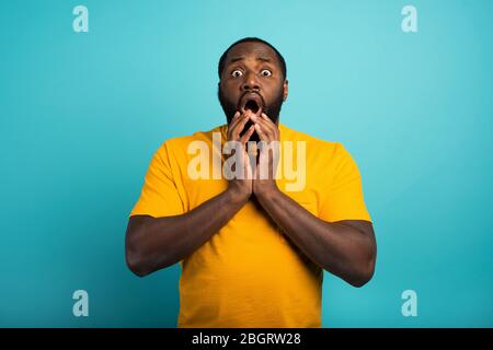 Surpris et choqué expression d'un garçon sur fond cyan Banque D'Images