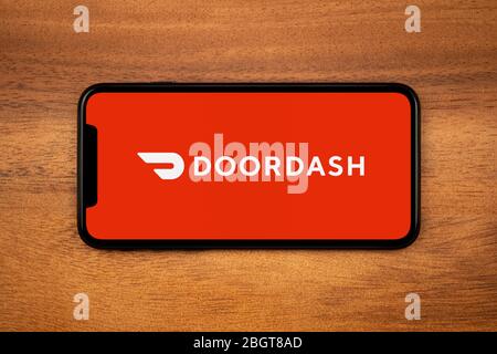 Un smartphone affichant le logo Doordash repose sur une table en bois ordinaire (usage éditorial uniquement). Banque D'Images