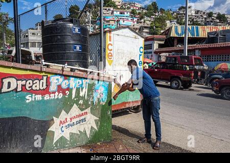 Jonel Saint Jean se lave les mains à un robinet public à Port-au-Prince, en Haïti. Le bureau du maire a installé environ 40 tours d’eau et près de 1,000 seaux à eau à des endroits clés de la capitale pour encourager le lavage des mains et empêcher la propagation du coronavirus. (Marie Michelle Felicien, GPJ Haïti) Banque D'Images