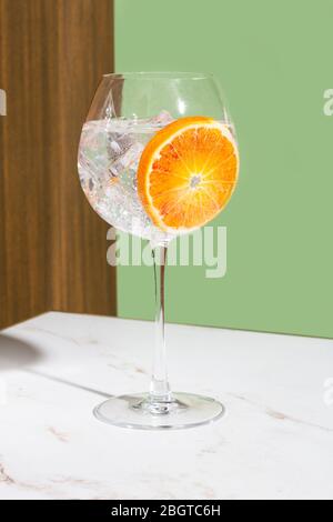 Cocktail tonique gin, garnie de tranches d'orange, fond coloré Banque D'Images