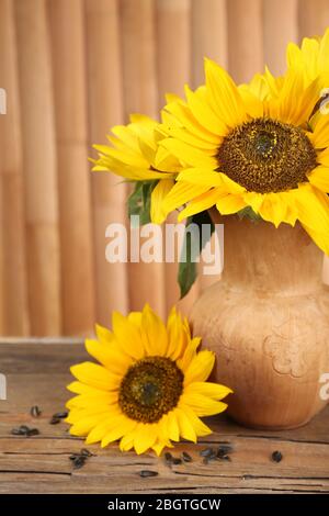 Beau bouquet de tournesols dans le pichet sur la table sur fond en bois Banque D'Images