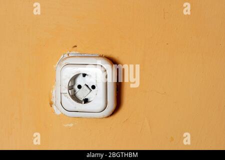 Prise d'alimentation sale sur un mur jaune. Banque D'Images