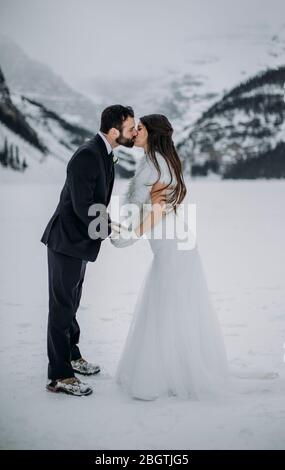 Couple nouvellement marié partage baiser sur le lac Louise gelé canada Banque D'Images