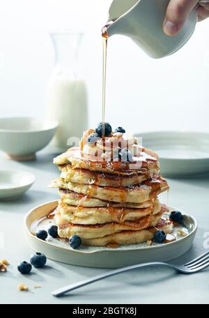 Pile de crêpes aux noix de banane bleu avec sirop petit déjeuner Banque D'Images