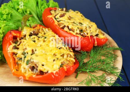 Poivrons rouges farcis avec des verts sur une table en bois à proximité Banque D'Images