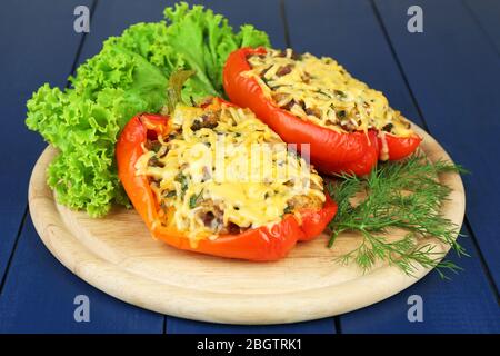 Poivrons rouges farcis avec des verts sur une table en bois à proximité Banque D'Images