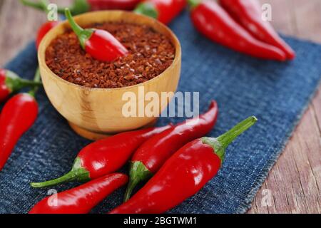 Poivrons rouges au piment chaud et poivre fraisé dans un bol sur une serviette en tissu couleur, sur fond en bois Banque D'Images