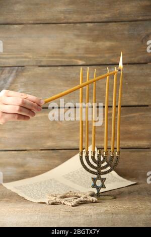 Bougies brûlantes à la main sur Menorah sur fond de bois Banque D'Images