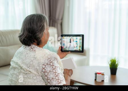 Femme asiatique senior utilisant la vidéoconférence, faire des consultations en ligne avec des services de consultation en pharmacie sur la maladie et les médicaments par appel vidéo. Télésanté, Banque D'Images
