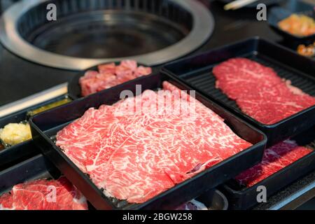 Assiettes de viande crue comme le bœuf de bonne qualité en tranches de bœuf de Wagyu, le porc, les sushis et la sauce à tremper. Préparé pour le barbecue traditionnel japonais également Banque D'Images