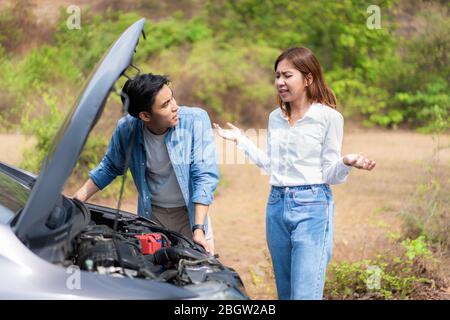 Un jeune couple asiatique avec un homme et une femme sur la route ayant un problème de panne de moteur de voiture sur la route et une femme regardant le stress quand un homme ne peut pas se représenter Banque D'Images