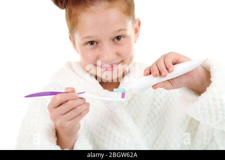 Belle petite fille dans peignoir tenant brosse à dents et dentifrice isolé sur blanc Banque D'Images