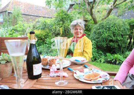 En été, la famille profite du thé de l'après-midi dans le jardin britannique avec thé et vin mousseux Banque D'Images