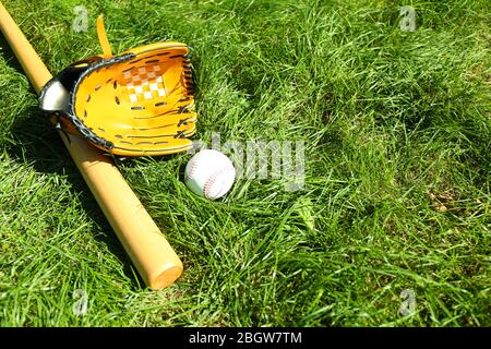 Batte de base-ball, balle et gant sur fond vert d'herbe Banque D'Images