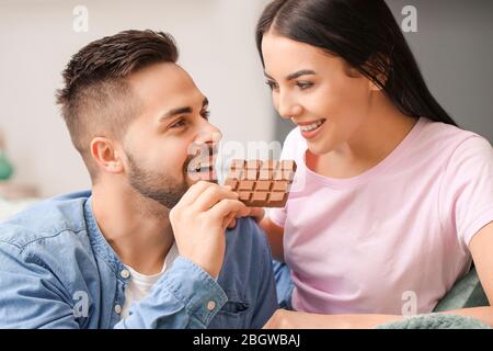 Beau couple de jeunes qui mangent du chocolat à la maison Banque D'Images