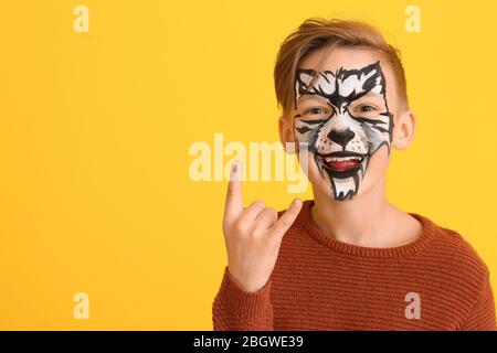 Petit garçon drôle avec peinture de visage sur fond de couleur Banque D'Images