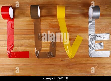 Mot d'amour formé avec des bandes de scotch colorées sur fond en bois Banque D'Images