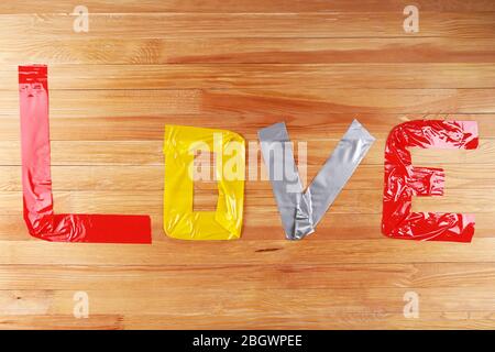 Mot d'amour formé avec des bandes de scotch colorées sur fond en bois Banque D'Images