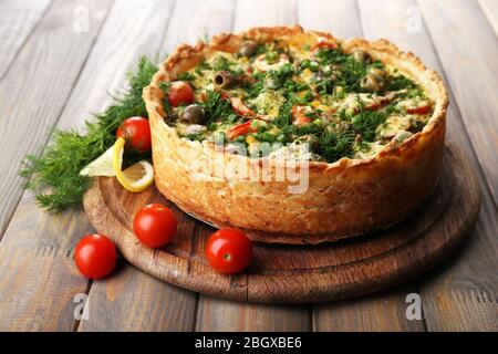 Tarte aux légumes avec brocoli, pois, tomates et fromage sur fond de bois Banque D'Images