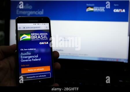 Minas Gerais, MG / Brésil - 22 avril 2020: Écran d'ordinateur et téléphone portable avec aide d'urgence page du Gouvernement brésilien, en analyse. Banque D'Images