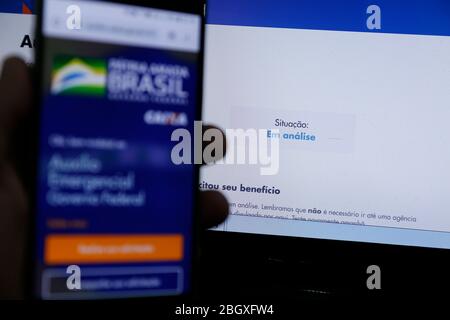 Minas Gerais, MG / Brésil - 22 avril 2020: Écran d'ordinateur et téléphone portable avec aide d'urgence page du Gouvernement brésilien, en analyse. Banque D'Images