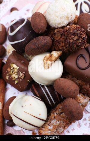 Tas de chocolats doux avec des grains de café sur des matériaux roses et des miily blanches sur fond de bois Banque D'Images