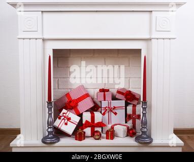 Cheminée avec boîtes de Noël et bougies sur parquet Banque D'Images